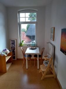 Zimmer mit einem Tisch, Stühlen und einem Fenster in der Unterkunft Schöne Wohnung, direkt an der Weser, mit Kaminofen in Hessisch Oldendorf