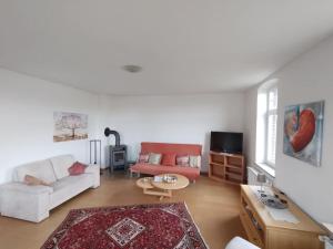 - un salon avec un canapé blanc et un fauteuil rouge dans l'établissement Schöne Wohnung, direkt an der Weser, mit Kaminofen, à Hessisch Oldendorf