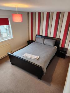 a bedroom with a bed with a striped wall at No 11 3 BED SERVICED APPARTMENT TOWN CENTRE in Girvan