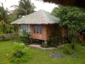 a small house with a thatched roof in a yard at Blue Seastar Cottages in Agpudlos