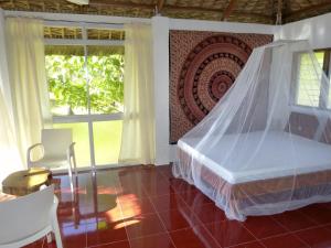 a bedroom with a bed with a mosquito net at Blue Seastar Cottages in Agpudlos
