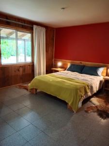 a bedroom with a bed with a red wall at Casa parcela Frutillar in Frutillar