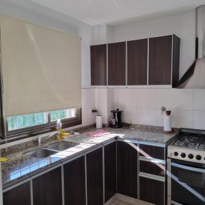 cocina con fregadero y fogones horno superior en Luminoso departamento en zona residencial en Mendoza