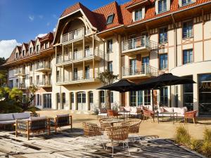 um pátio com cadeiras e mesas e um edifício em TRIBE Hôtel Le Touquet em Le Touquet-Paris-Plage