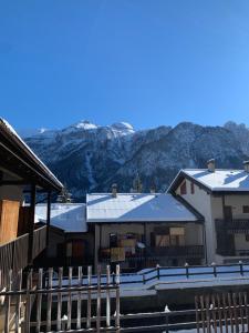 a building with snow covered roofs with mountains in the background at Casa vacanza Folgarida in Folgarida