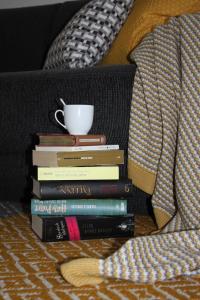 a stack of books sitting on a bed with a coffee cup at Appartement Hauptbahnhof in Nuremberg