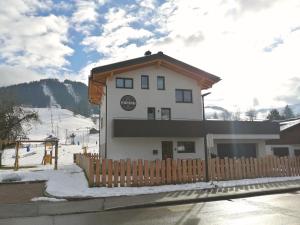 un bâtiment avec une clôture en bois dans la neige dans l'établissement Das Prinzenberg Appartement, à Maria Alm