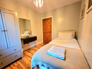 a small bedroom with a bed and a wooden floor at Colleton Cottage at Lovelady Shield- With Hot Tub in Alston