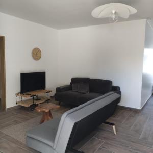 a living room with a black couch and a tv at Les Villas RIO Saint André in Saint-André