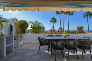 a patio with a table and chairs and palm trees at Molo Bahia Apartment Near the beach in Marbella