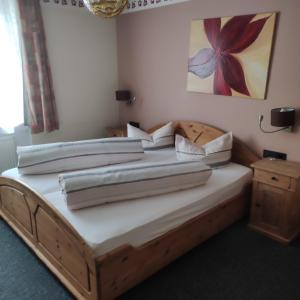 a bedroom with a wooden bed with white sheets at Gasthof Goldene Krone in Selbitz