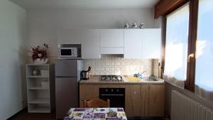 una pequeña cocina con armarios blancos, mesa y fregadero en Apartment with garden, lake view and parking - Larihome A15, en Domaso
