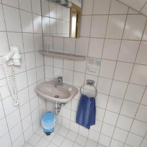 a white tiled bathroom with a sink and a mirror at Gasthof Goldene Krone in Selbitz