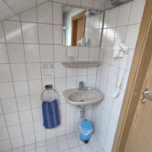 uma casa de banho em azulejos brancos com um lavatório e um espelho. em Gasthof Goldene Krone em Selbitz