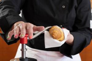 une personne tient un croissant sur un couteau dans l'établissement Hotel Il Duca d'Este, à Ferrare