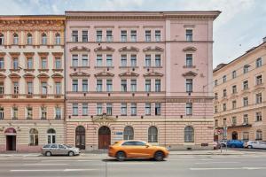 an orange car driving in front of a large building at Designer Studio in New Town by Prague Days in Prague