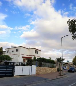 uma casa branca com uma cerca em frente a uma rua em Glezant em Mitzpe Ramon