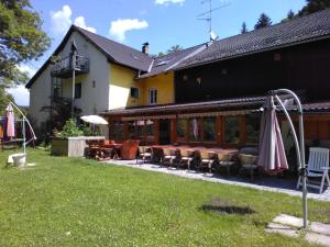 ein Gebäude mit einer Terrasse mit Tischen und Stühlen in der Unterkunft Urlaubspension Die Mühle in Schöllnach