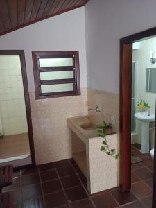 een badkamer met een bad, een wastafel en een spiegel bij RESONAMUH - Hostel in São Pedro da Aldeia