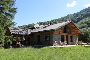 a log cabin in a field with mountains in the background at Chalet de l’Alpette in Valloire