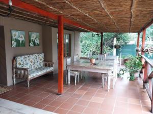 um pátio com uma mesa e cadeiras num alpendre em Lily Guesthouse em Bloemfontein