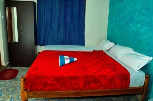a bed with a red comforter with a tie on it at Seven Endue Cottages in Ooty