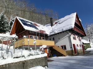 una casa con nieve en el techo en Ferienwohnung Sonnenblick, en Oberharmersbach