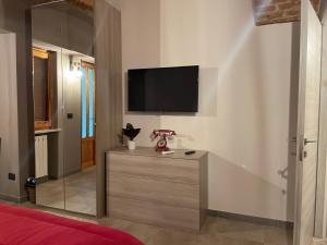 a bedroom with a tv on the wall and a dresser at HappyHome Bilocale centro storico Rivarolo Canavese in Rivarolo Canavese