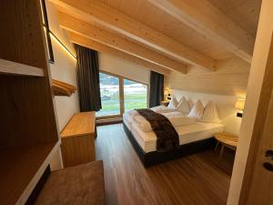 ein Schlafzimmer mit einem Bett und einem großen Fenster in der Unterkunft Dorferwirt in Bramberg am Wildkogel