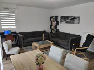 a living room with a couch and a table and chairs at App 5 pers, parking, 3mn RER A, 40 mn du centre de Paris, Cergy le Haut in Cergy
