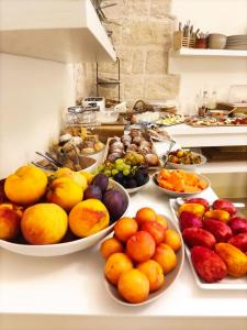 un buffet de fruits et légumes dans des bols sur un comptoir dans l'établissement Antico Mondo Rooms & Suites, à Polignano a Mare