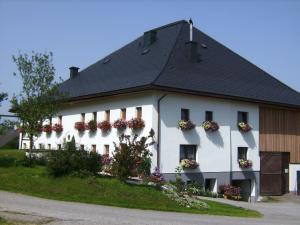 ein weißes Gebäude mit schwarzem Dach in der Unterkunft Feichtingerhof in Steinbach am Attersee