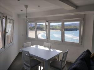 a dining room with a table and chairs and windows at Casa Consuelo Malpica in Malpica +5 photos