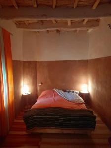 a bedroom with a bed with two lights on it at Les Jardins du M'goun in Kalaat MGouna