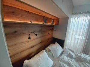 a bed with a wooden headboard and two pillows at Apartment Deluxe Ossiacher See - Gerlitzen in Sattendorf