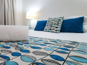 um quarto com uma cama com um tapete azul e branco em Marlin Waters Beachfront Apartments em Palm Cove