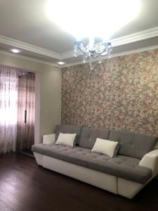 - un salon avec un canapé gris et du papier peint floral dans l'établissement Уютная квартира у парка, à Chişinău