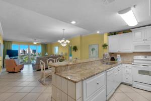 a kitchen with white cabinets and a living room at Leeward Key 401 in Destin
