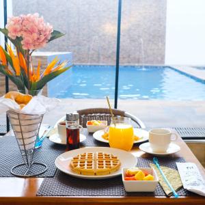 a table with breakfast foods and drinks and a pool at Hotel Bella Isa in La Dorada