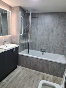 een badkamer met een douche, een bad en een wastafel bij Forth View Apartment in Stirling