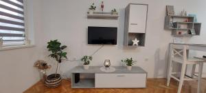 a living room with a table and a tv on a wall at Apartman Bart in Subotica