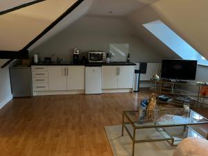 an attic kitchen with white cabinets and a table at The Pheasantry - guest house in beautiful rural location in Aldermaston