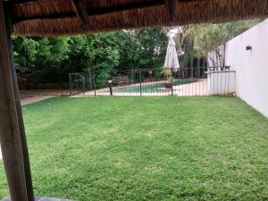 einen Hof mit einem Zaun und einem Regenschirm in der Unterkunft CONSTANTIA GUEST LODGE in Pretoria