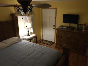 a bedroom with a bed and a dresser with a television at Chateau DeVille of West Shreveport in Greenwood