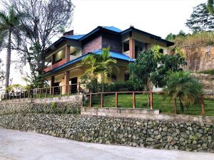une maison au-dessus d'un mur en pierre dans l'établissement Green Village By Hospedify, Hermosa Villa En Las Alturas con Piscina, Billar, y BBQ, à Jarabacoa