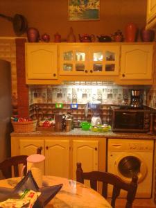 a kitchen with yellow cabinets and a table and a microwave at Maison de rêve in Tabarka