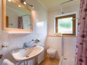 W łazience znajduje się umywalka, toaleta i lustro. w obiekcie Gästehaus Anker w mieście Walchsee
