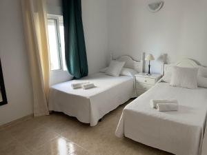 2 camas en una habitación blanca con ventana en Apartamentos Dulcemar Frente al Mar con zona SPA, en San José