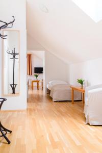 a white bedroom with a bed and a wooden floor at Stranachwirt Apartments in Sankt Michael im Lungau