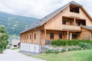 a wooden house on a hill with mountains in the background at Stranachwirt Apartments in Sankt Michael im Lungau